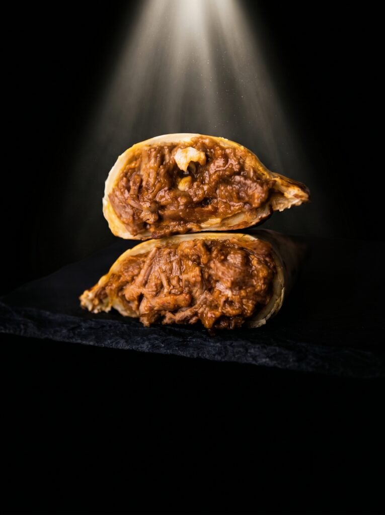 Vista superior de una auténtica empanada argentina de ternera cortada a cuchillo y cebolla caramelizada, horneada y servida en un plato oscuro de Empanada Club.